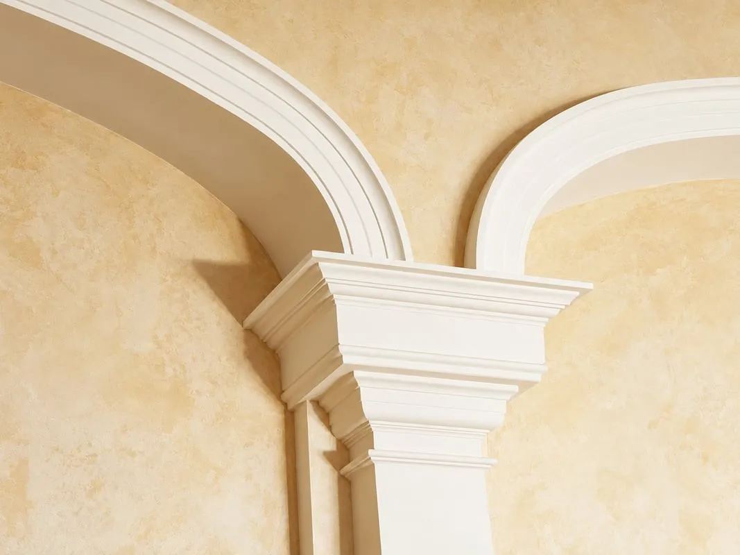 Arc décoratif et chapiteau moulurés sur un mur enduit